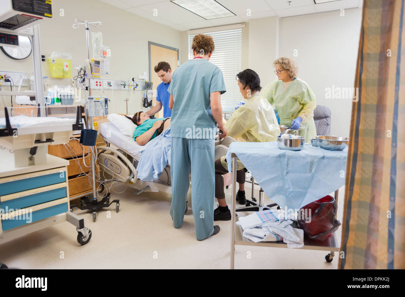 Il team medico operante la donna incinta mentre il marito in attesa Foto Stock