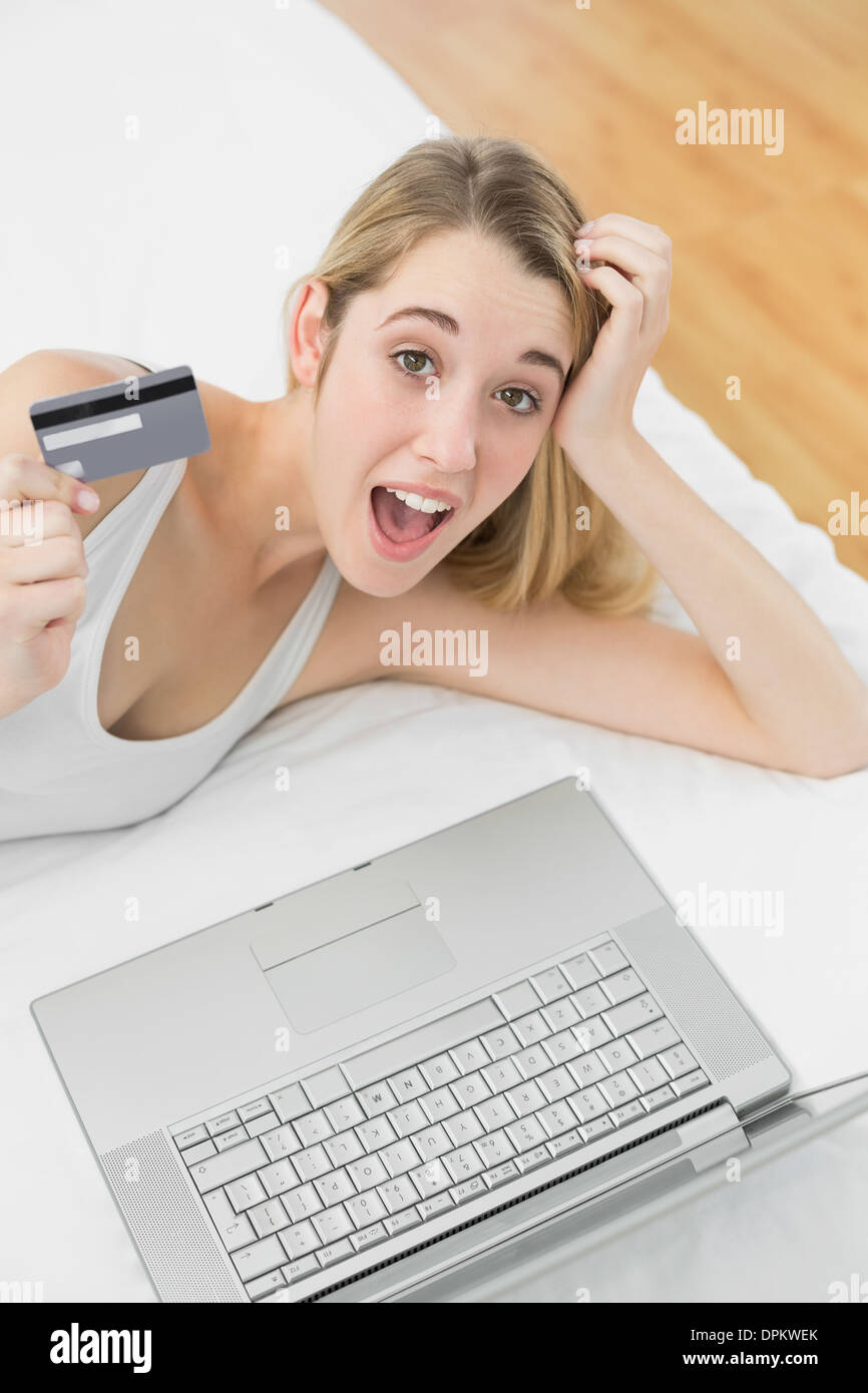Successo sorpreso donna home shopping con il suo notebook guardando la fotocamera Foto Stock