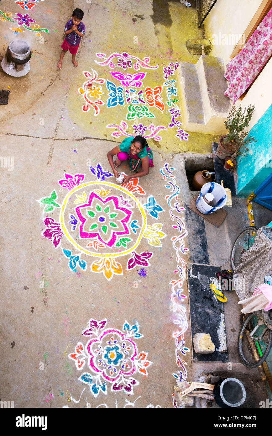 Ragazza indiana rendendo Rangoli festival di polvere colorata progetta a Sankranti in un territorio rurale villaggio indiano. Andhra Pradesh, India Foto Stock