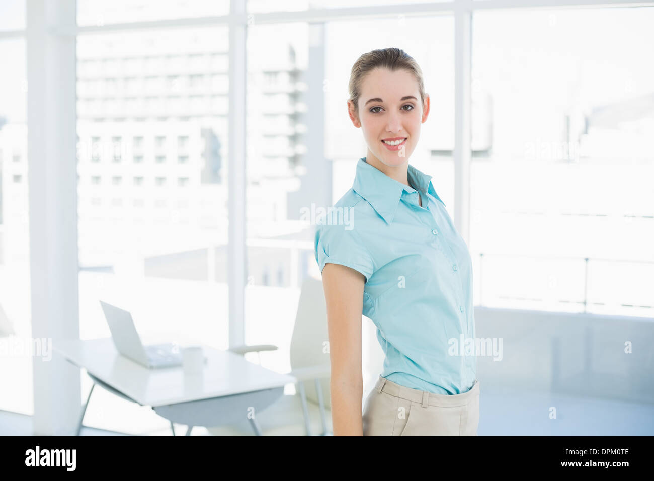 Splendida imprenditrice indossa camicetta blu in posa nel suo ufficio Foto Stock