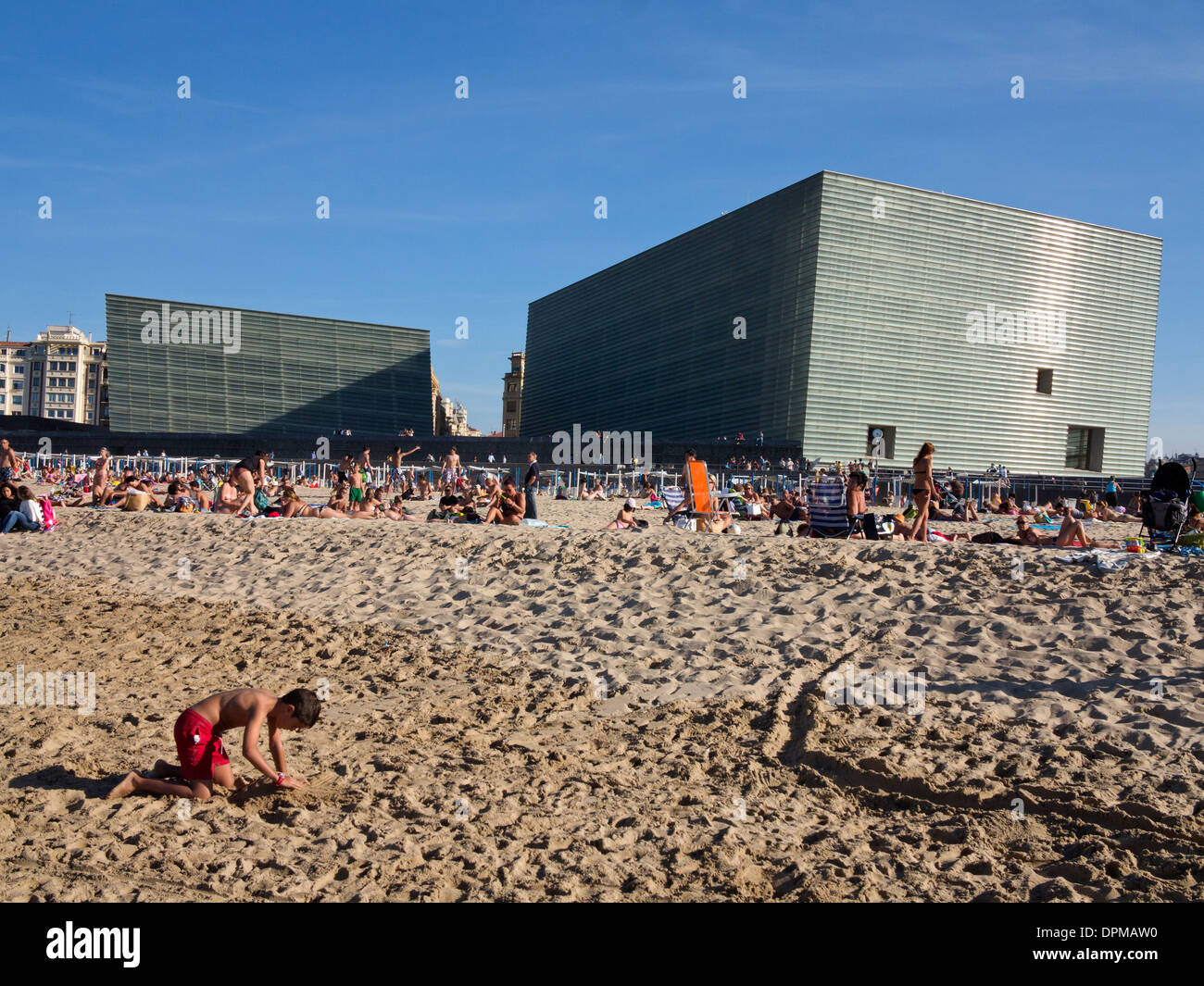 Lucertole da mare e nuotatori sulla spiaggia Zurriola con centro congressi Kursaal e auditorium in background, San Sebastian, Spagna Foto Stock