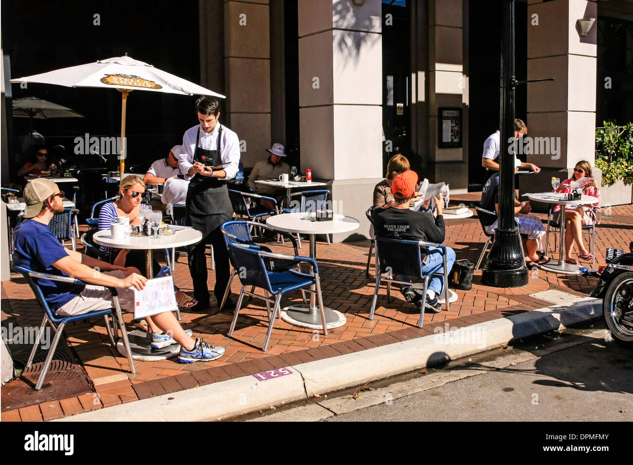 Le persone che si godono il sole invernale in Florida da mangiare al fresco presso un cafè sul marciapiede Foto Stock