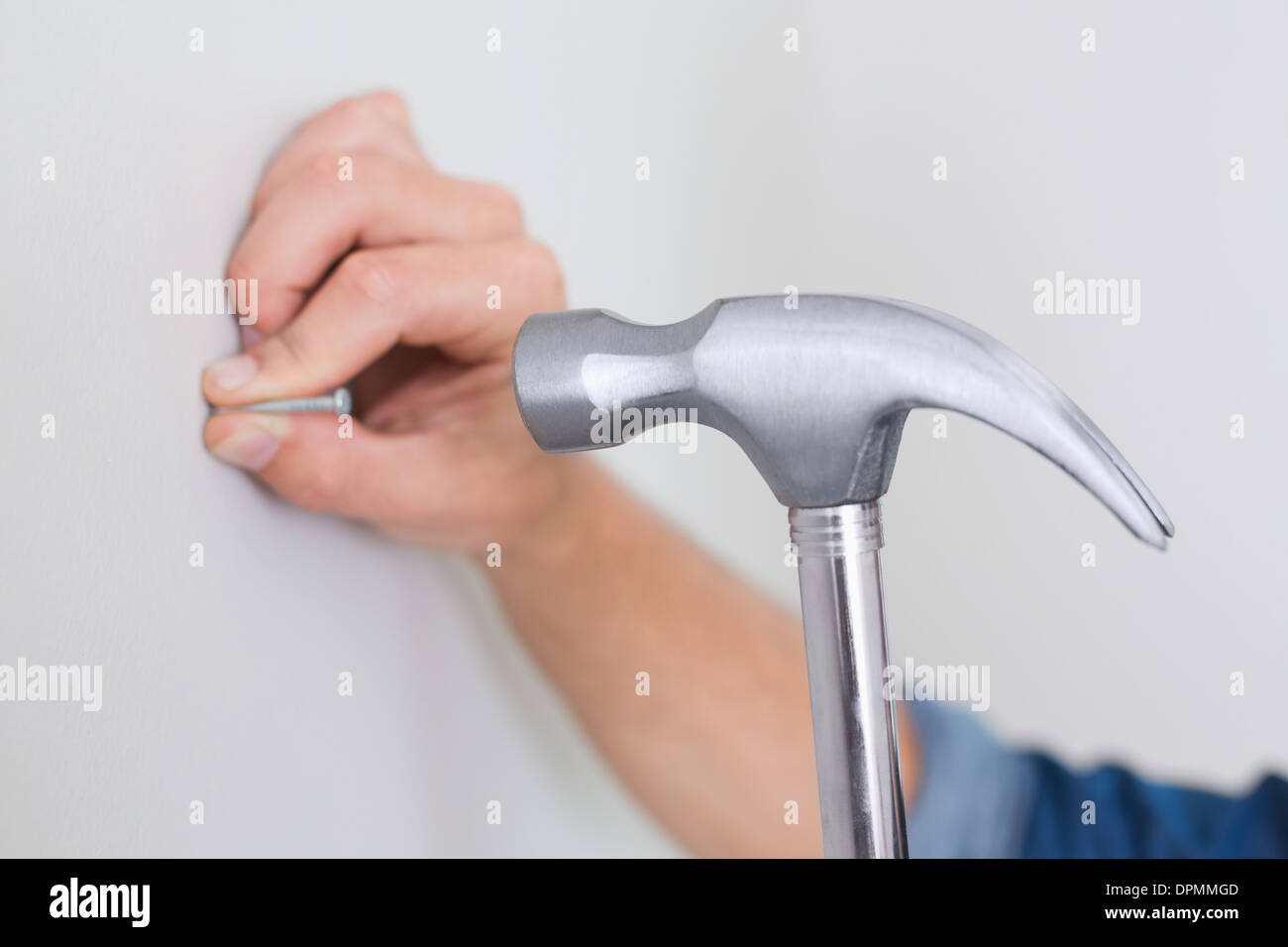 Mani martellamento chiodo nella parete Foto Stock