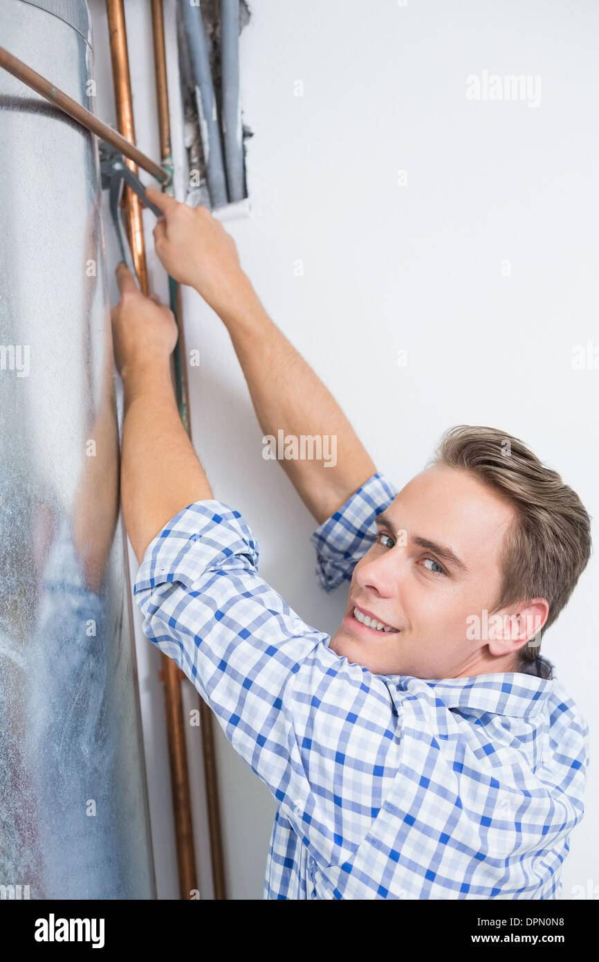 Il tecnico della manutenzione di un riscaldatore di acqua calda' tubi Foto Stock
