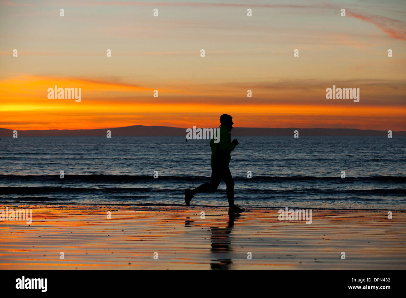 Persone corrono lungo la spiaggia di Weston Super Mare Foto Stock