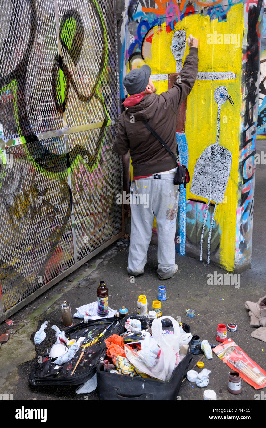 Londra, Inghilterra, Regno Unito. Undercroft sotto il Teatro Nazionale sulla banca del sud - sede per la corsa su skateboard. Graffiti artista al lavoro Foto Stock