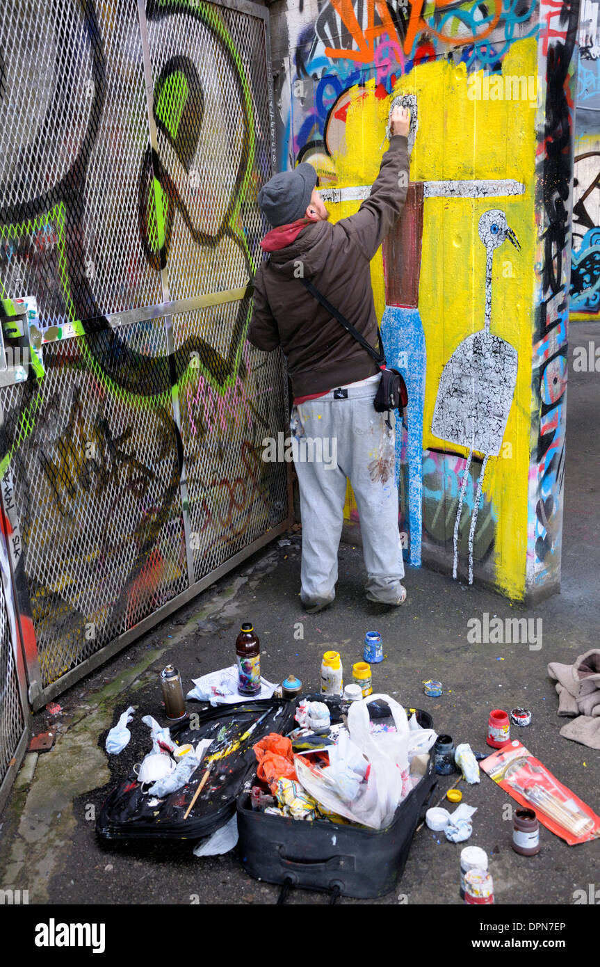 Londra, Inghilterra, Regno Unito. Undercroft sotto il Teatro Nazionale sulla banca del sud - sede per la corsa su skateboard. Graffiti artista al lavoro Foto Stock