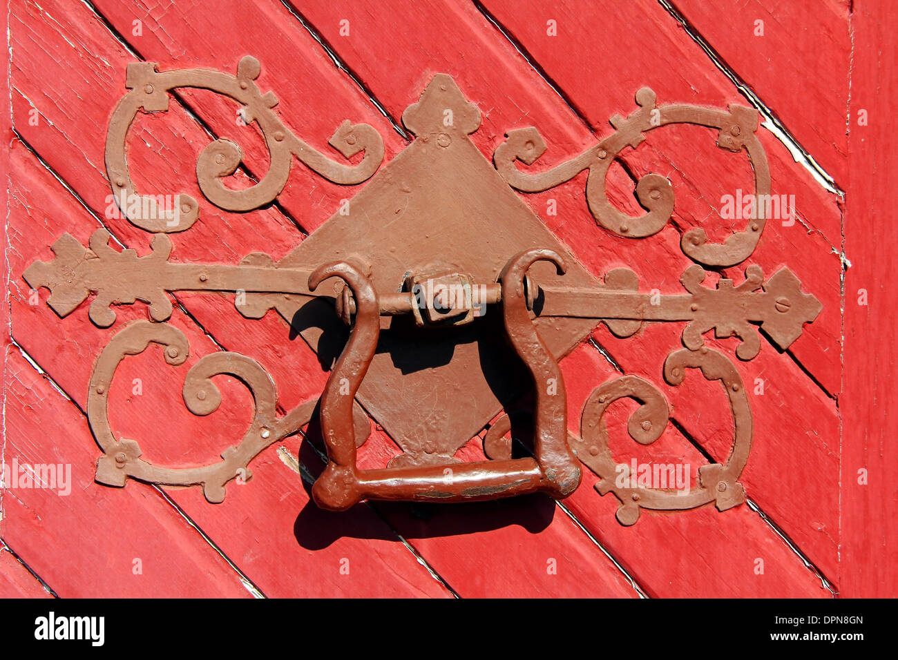 In prossimità di un antico ornata maniglia della porta su una Rossa porta di legno. Foto Stock
