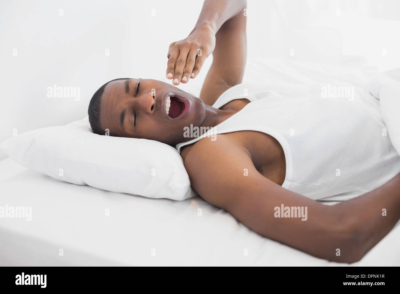 Assonnato Afro uomo sbadigliare a letto Foto Stock