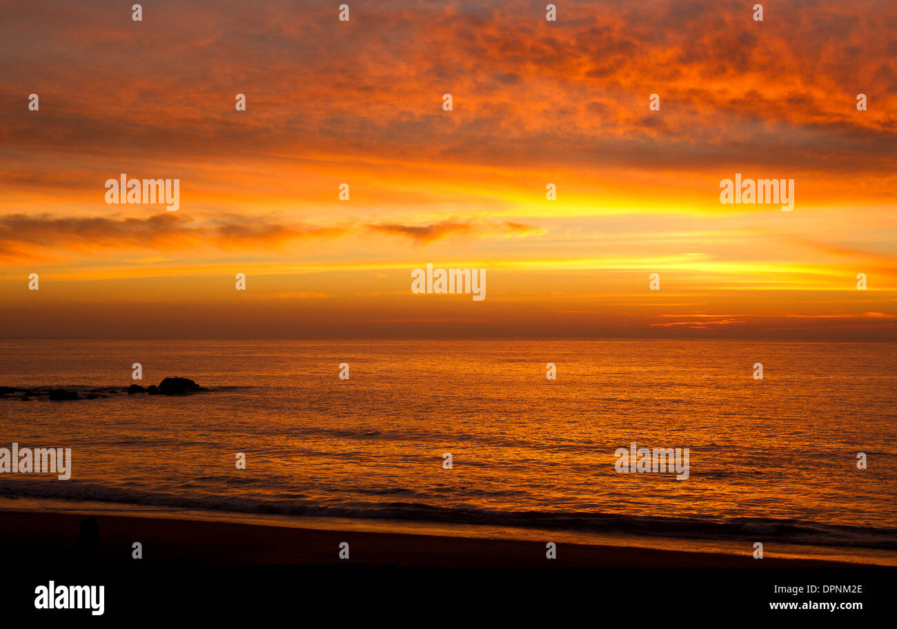 Calde nuvole arancioni al tramonto che si riflettono nell'Oceano Pacifico Foto Stock