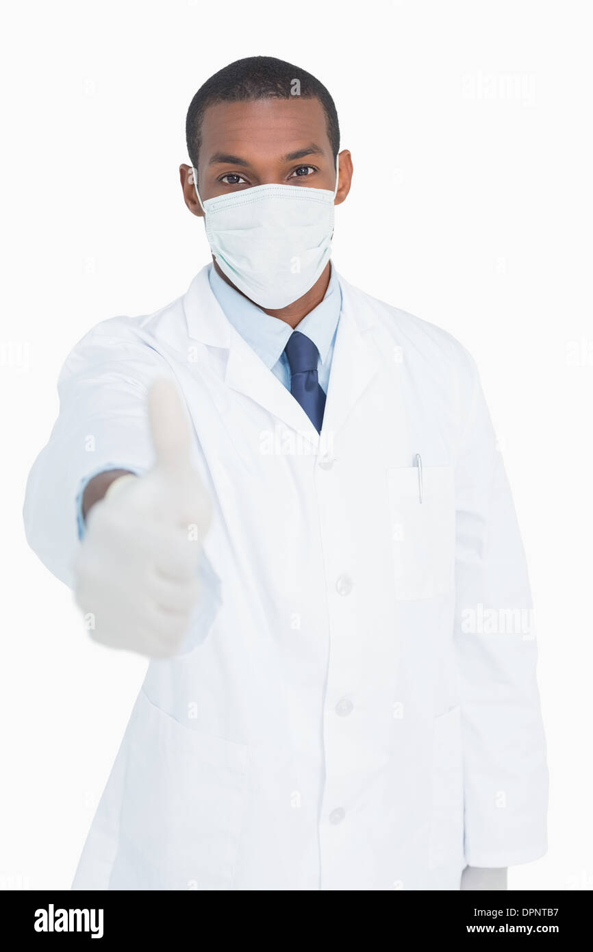 Ritratto di medico maschio in maschera gesticolando pollice in alto Foto Stock