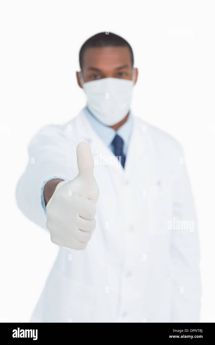 Ritratto di medico maschio in maschera gesticolando pollice in alto Foto Stock
