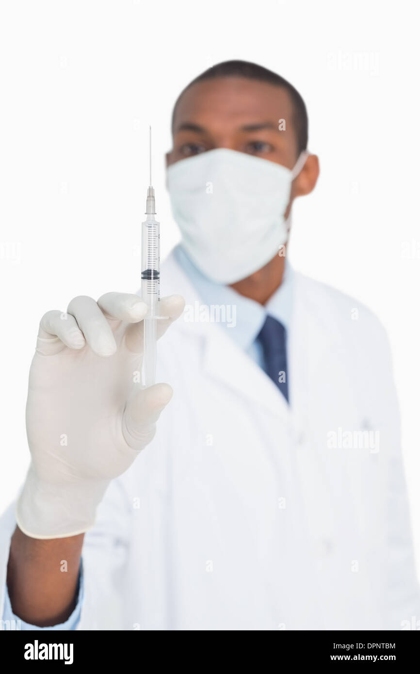 Medico maschio in maschera e guanto tenendo una iniezione Foto Stock