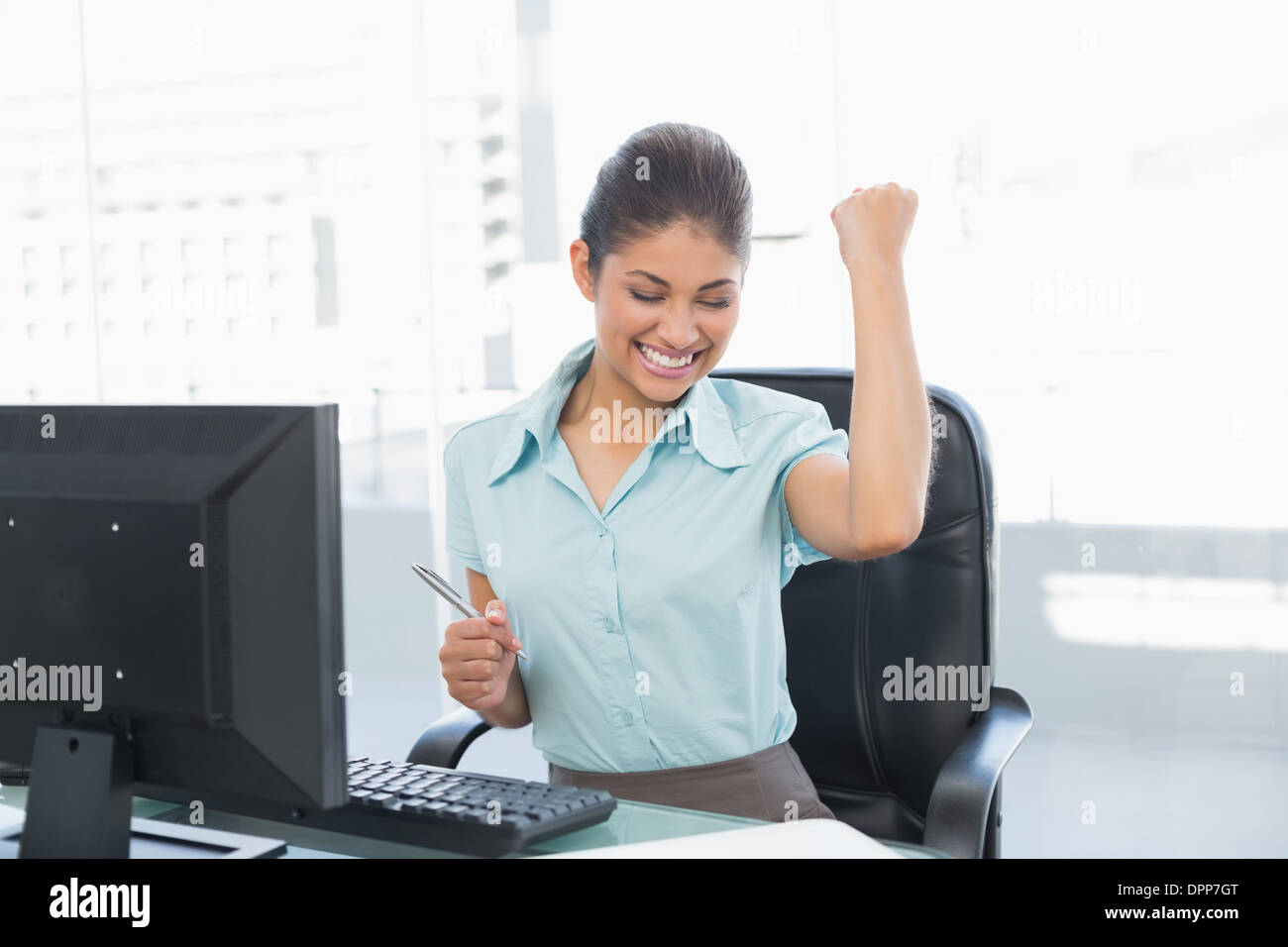 Felice imprenditrice del pugno di aggraffaggio alla scrivania in ufficio Foto Stock