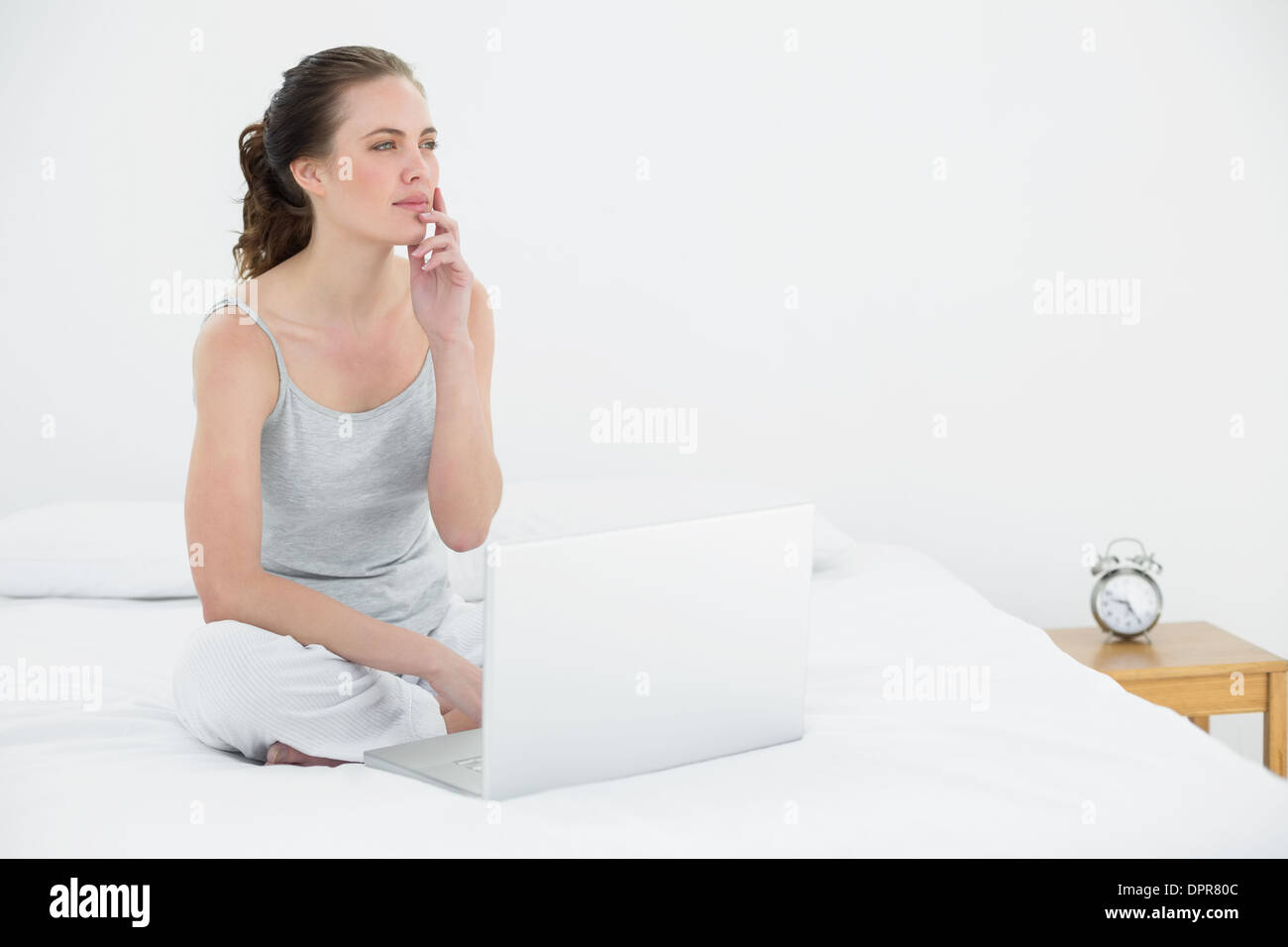 Premurosa donna informale con il computer portatile a letto Foto Stock