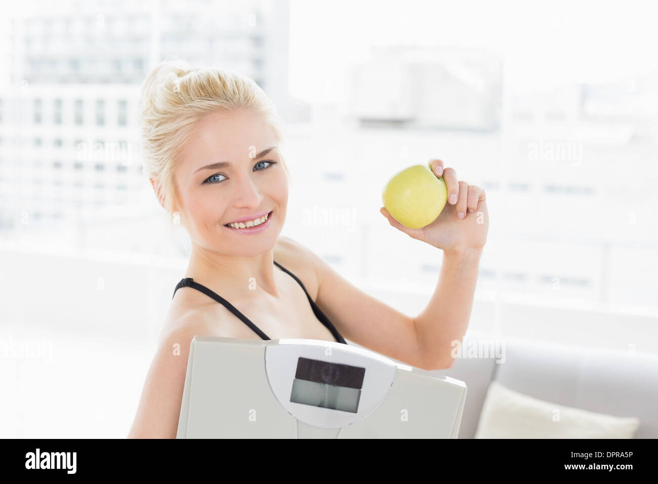 Montare donna scala di contenimento e Apple in studio fitness Foto Stock