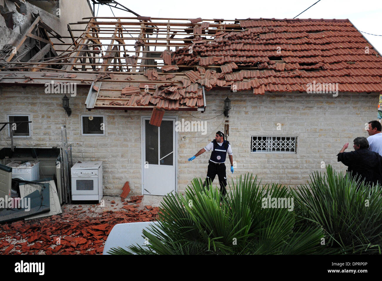 30 dic 2008 - sderot, Israele - un medic evacua una casa che è stato colpito da un razzo Kassam a pochi attimi prima che crolla in western Negev città di Sderot martedì. Una persona è stato leggermente ferito da schegge e altri tre hanno subito urti. Un altro razzo è atterrato a circa 500 metri di distanza mentre un terzo ha colpito una città cimitero. Due razzi più colpito aree aperte. Almeno 60 razzi hav Foto Stock