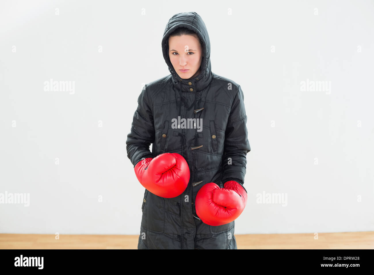 Donna dura in giacca con cappuccio rosso e guantoni da pugilato Foto Stock