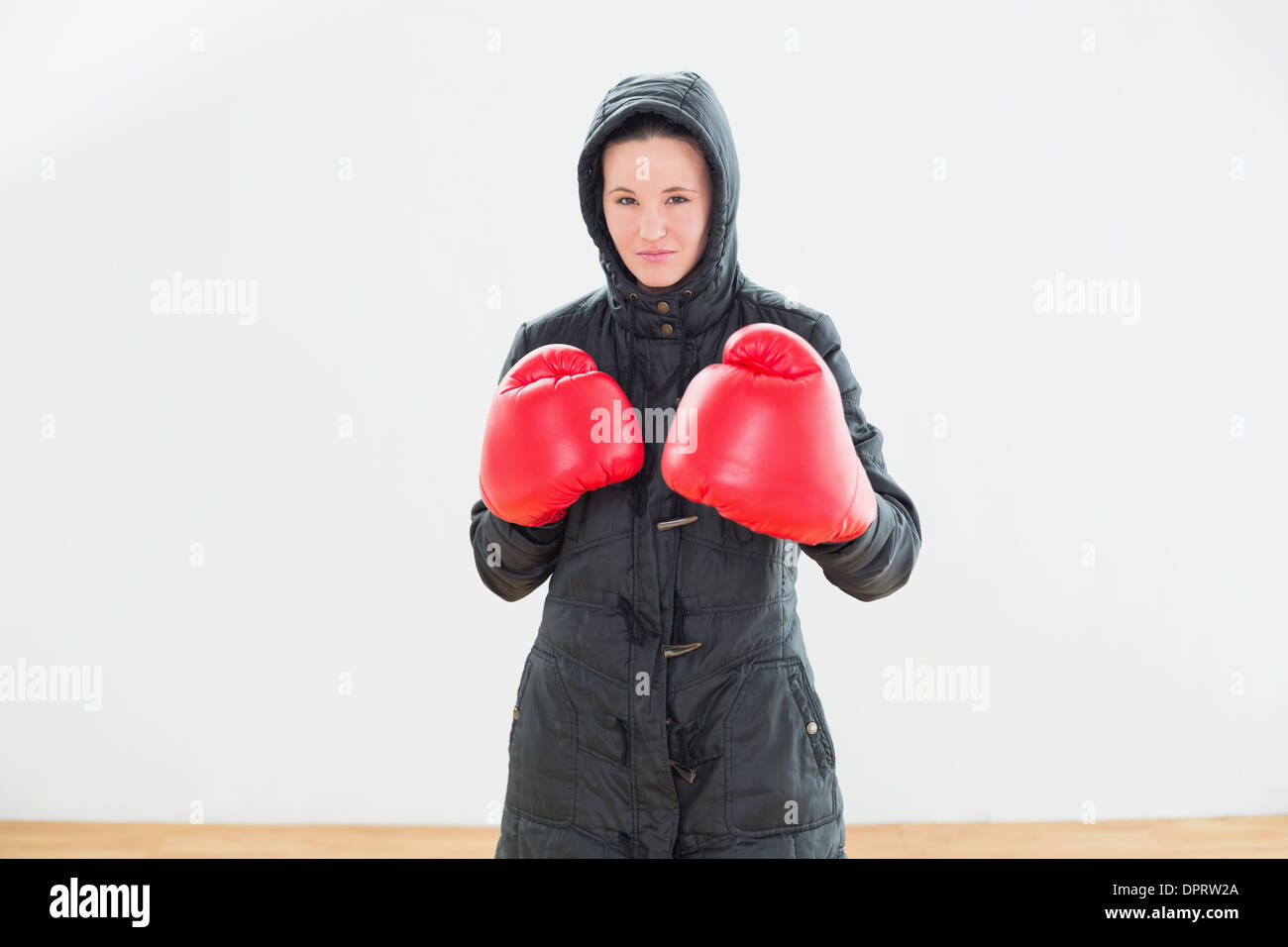 Donna dura in giacca con cappuccio rosso e guantoni da pugilato Foto Stock