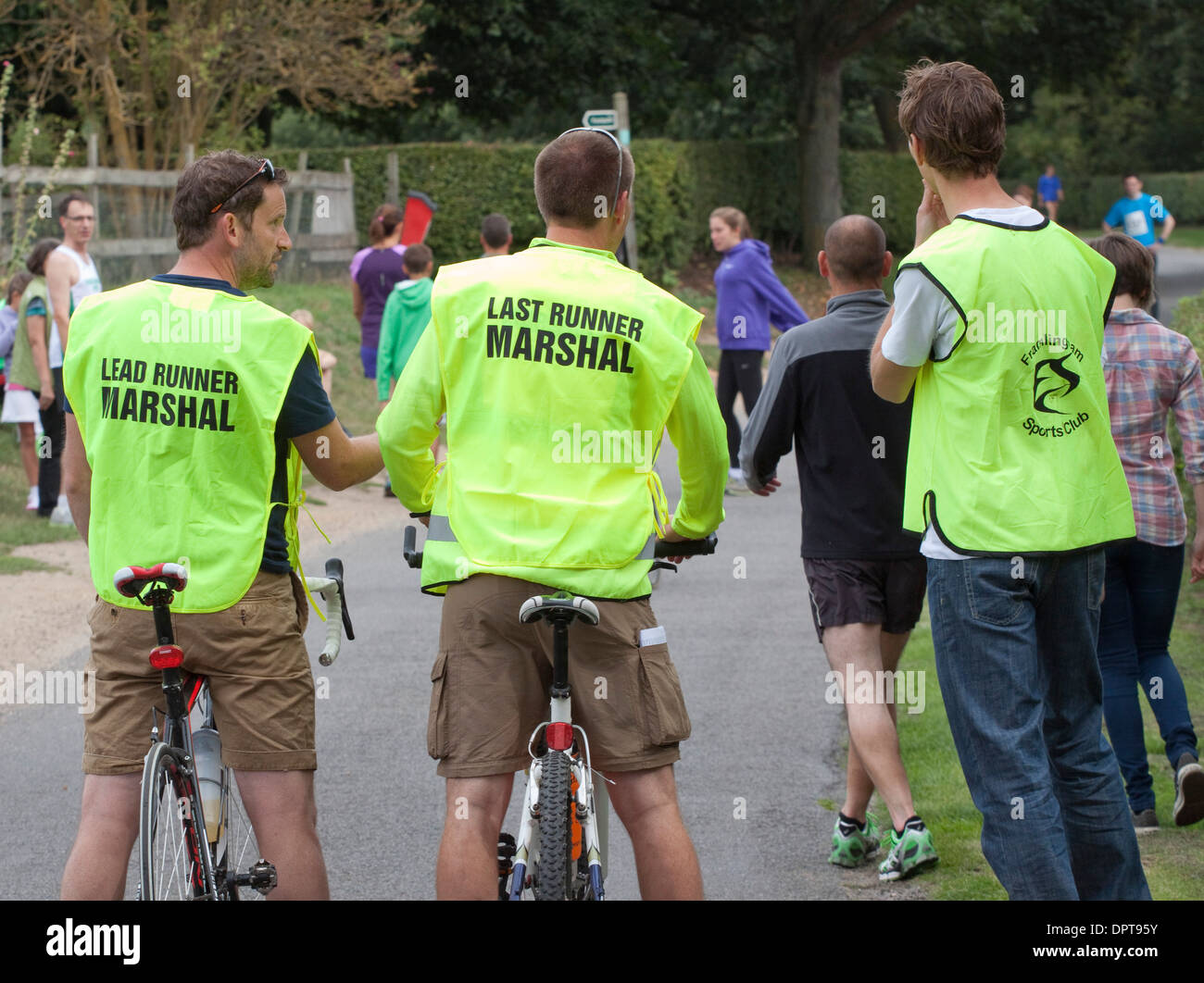 Esegue il marshalling indossando il piombo e ultimo Runner dayglo bibs/tabards Foto Stock