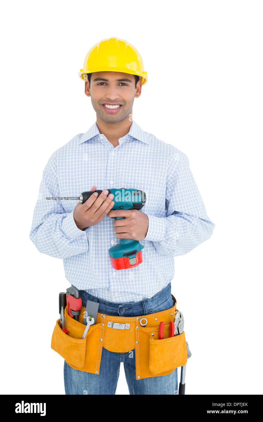 Sorridente bel giovane tuttofare in hard hat holding drill Foto Stock