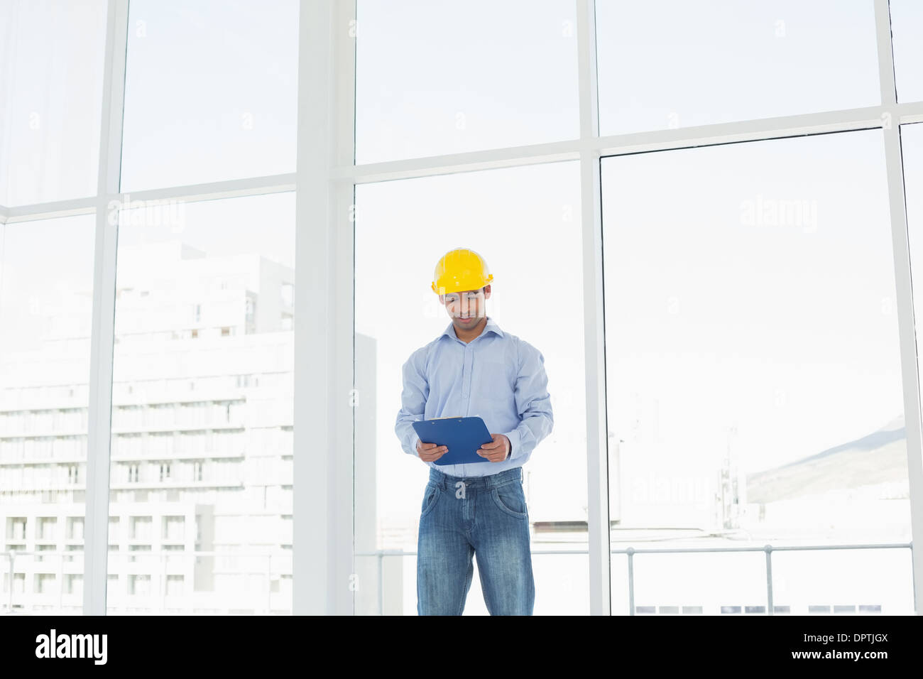 Architetto sorridente nel casco giallo con appunti di office Foto Stock