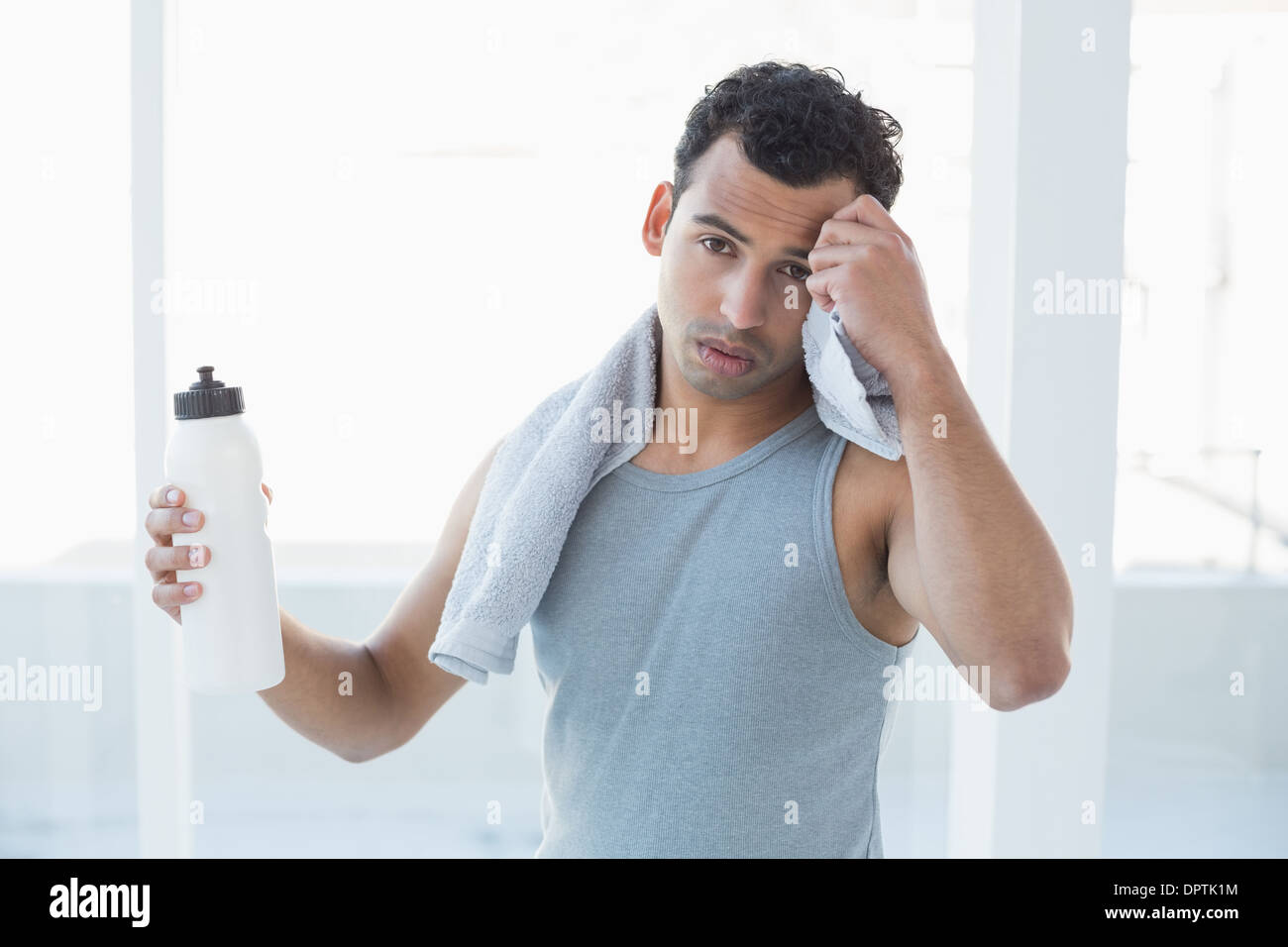 Giovane uomo tergi sudore con asciugamano in studio fitness Foto Stock