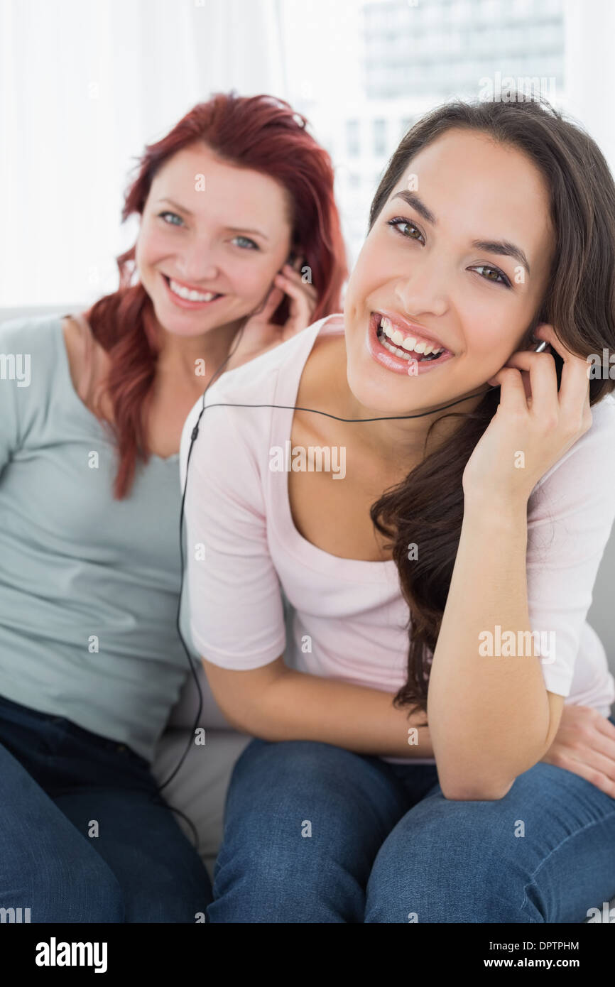 Allegro amici ascoltando la musica tramite auricolari insieme Foto Stock