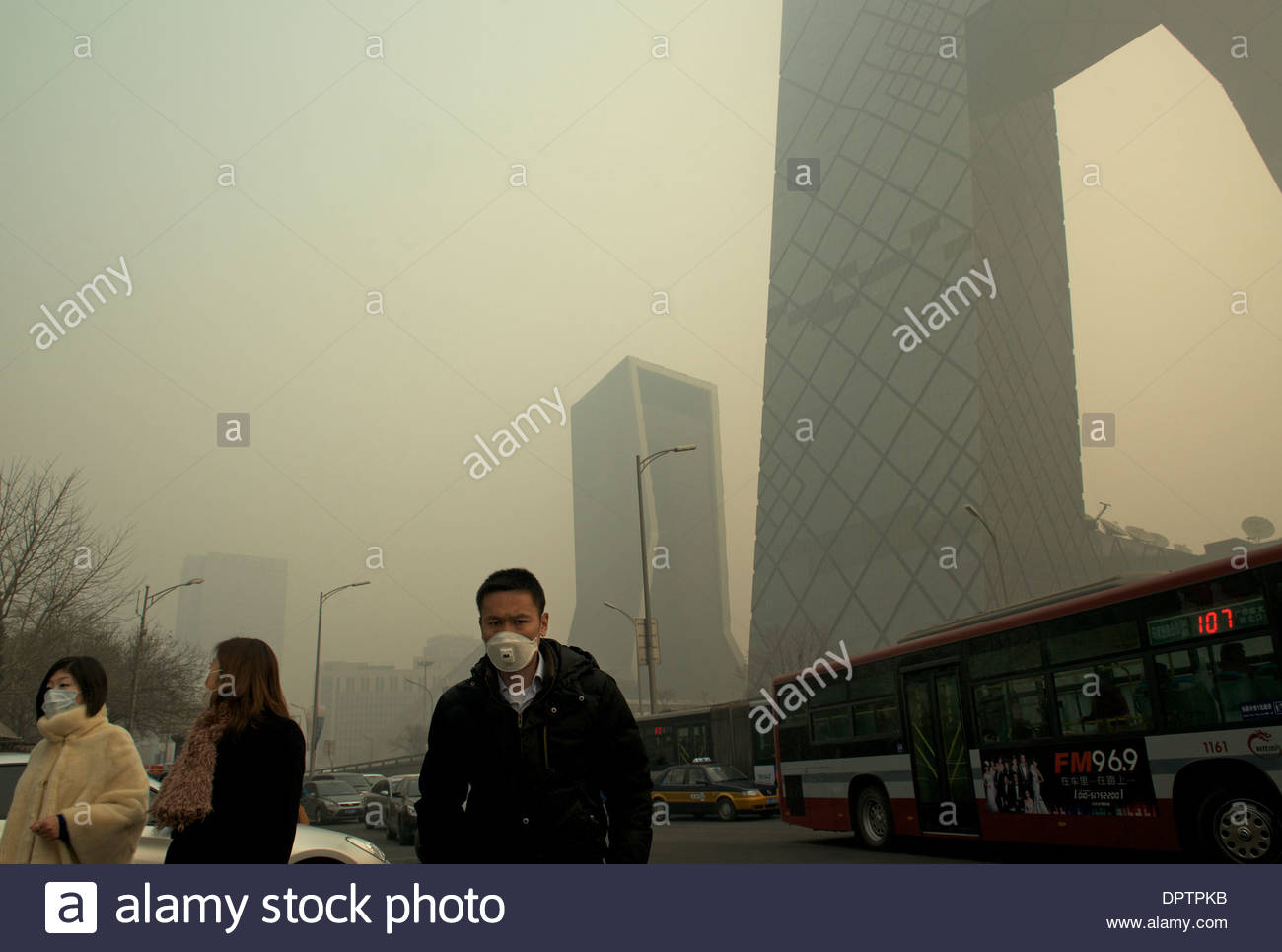 Persone indossare maschere passato Cina CCTV (Televisione della Cina Centrale) sede di un forte inquinamento atmosferico che copre di Pechino. 2014 Foto Stock