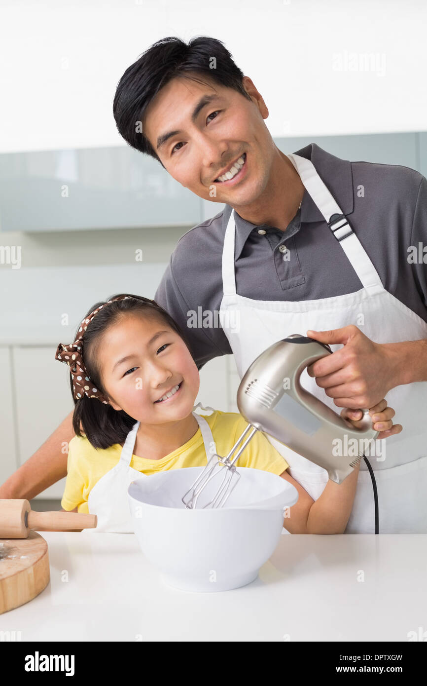 L'uomo con sua figlia con frusta elettrica nella ciotola in cucina Foto Stock
