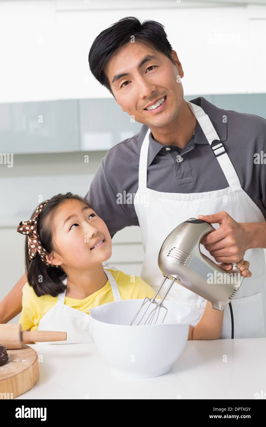 L'uomo con sua figlia con frusta elettrica nella ciotola in cucina Foto Stock