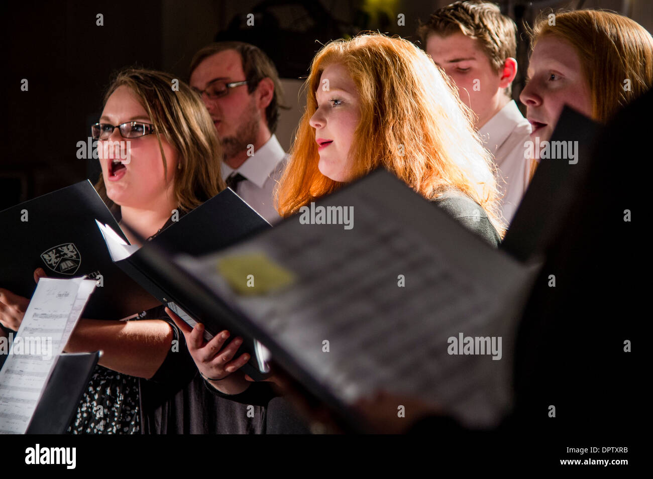 Un gruppo di Aberystwyth gli studenti universitari di uomini e donne a mantenere la lamiera musica canto in un coro amatoriale, REGNO UNITO Foto Stock
