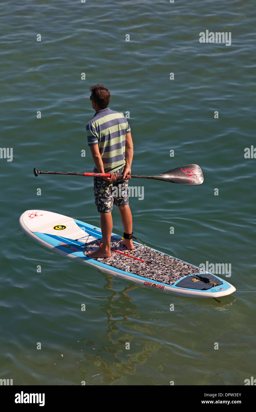 Paddle boarder in piedi sul suo bordo di mare a Bournemouth in agosto Foto Stock