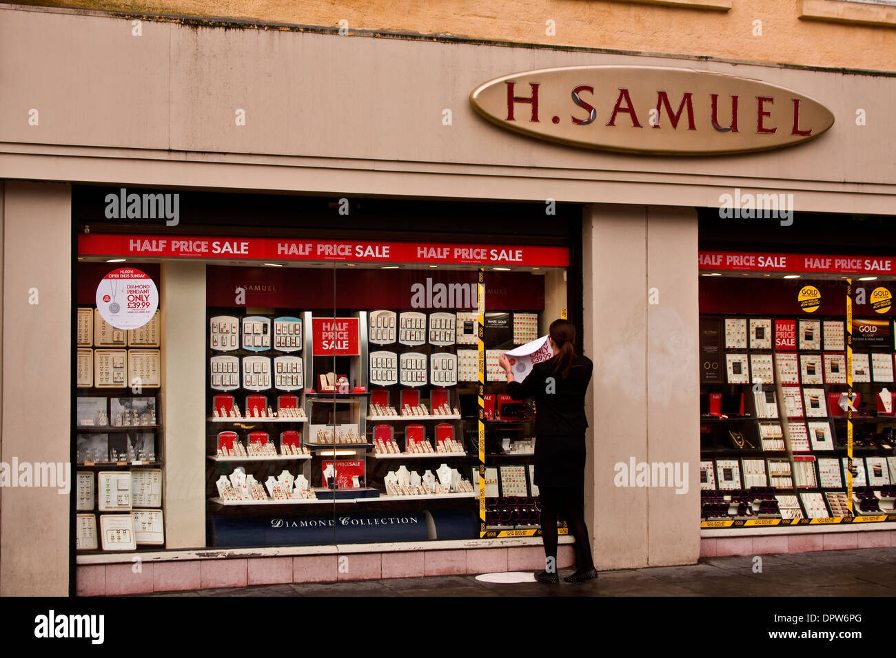 H Samuel gioiellerie assistente retail mettendo a gennaio vendite poster sulla pubblicità di windows Diamond pendenti a Dundee, Regno Unito Foto Stock