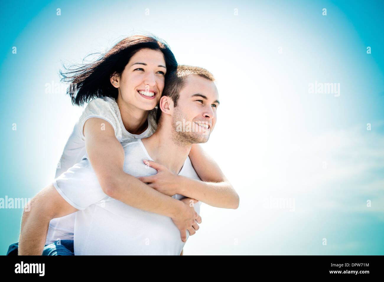 Coppia giovane guardando al futuro luminoso - donna felice abbracciando il suo amore attorno al collo Foto Stock