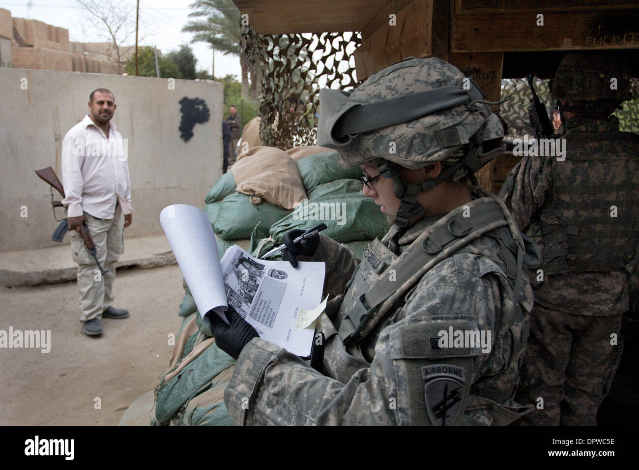 Dic 21, 2008 - Baghdad in Iraq - STATI UNITI Specialista dell'esercito FITZGERALD recensioni le informazioni dei proprietari di imprese di applicare per un business di concedere in Ghazalia quartiere di Baghdad mentre un membro dei figli di Iraq sta di guardia. (Credito Immagine: © John Goodman/ZUMA Press) Foto Stock