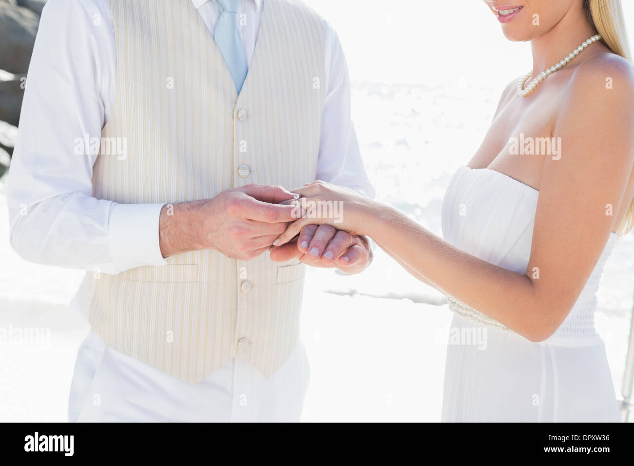 L'uomo posizionando l'anello sul sorridente brides dito Foto Stock