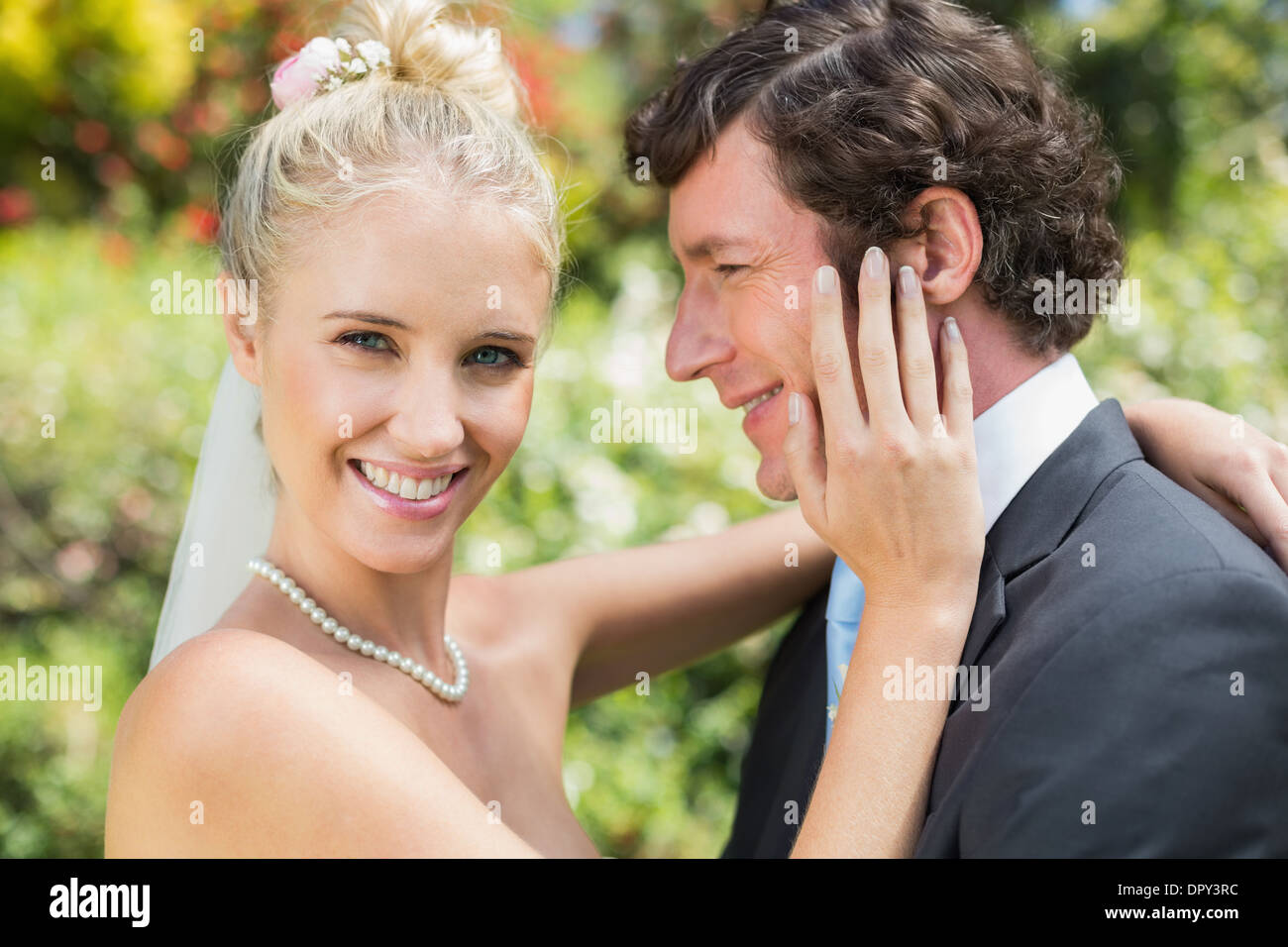 Graziosa moglie toccando il suo nuovo mariti guancia sorridente in telecamera Foto Stock