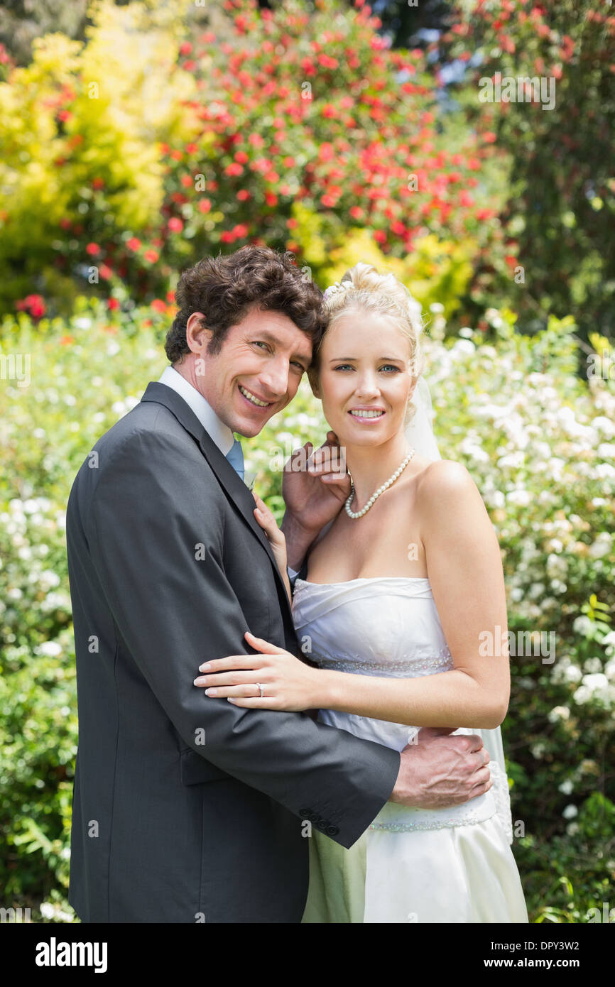 Romantico lieto sposi novelli abbracciando guardando la fotocamera Foto Stock
