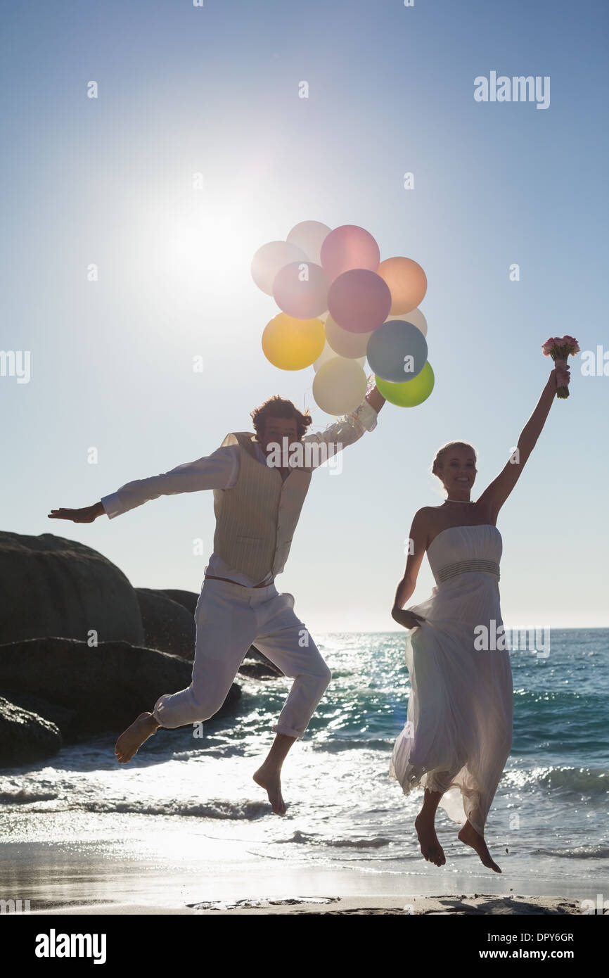 Lo sposo holding palloncini e sposa bouquet di contenimento jumping Foto Stock