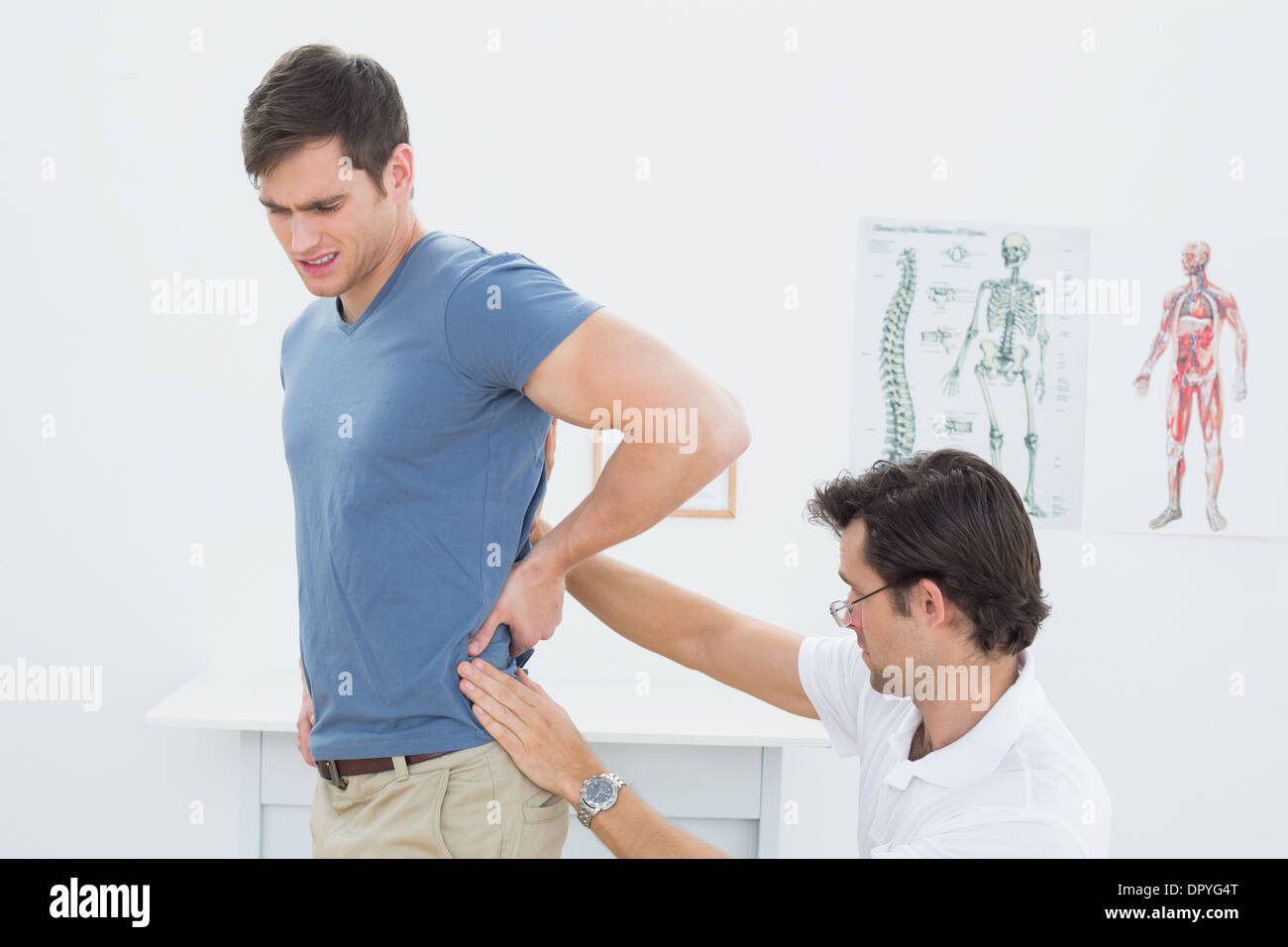 Vista laterale di un maschio di fisioterapista esaminando le mans indietro Foto Stock
