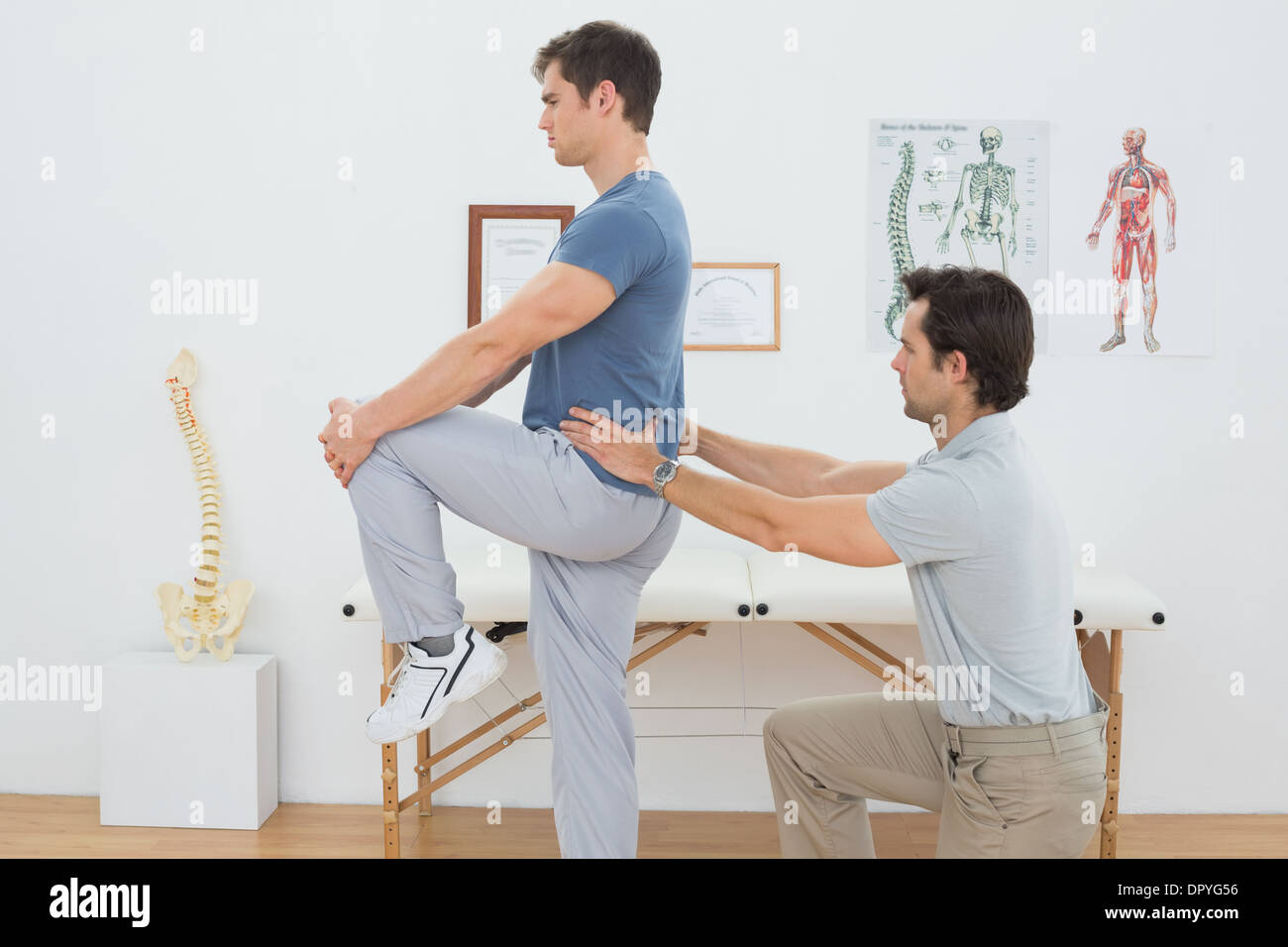 Vista laterale di un maschio di fisioterapista esaminando le mans indietro Foto Stock
