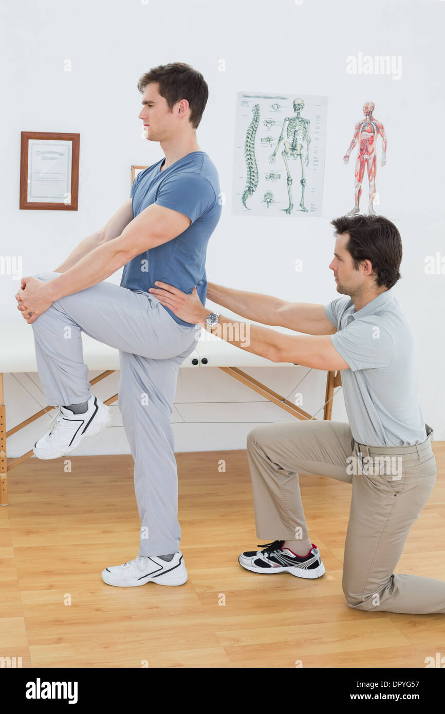 Vista laterale di un maschio di fisioterapista esaminando le mans indietro Foto Stock