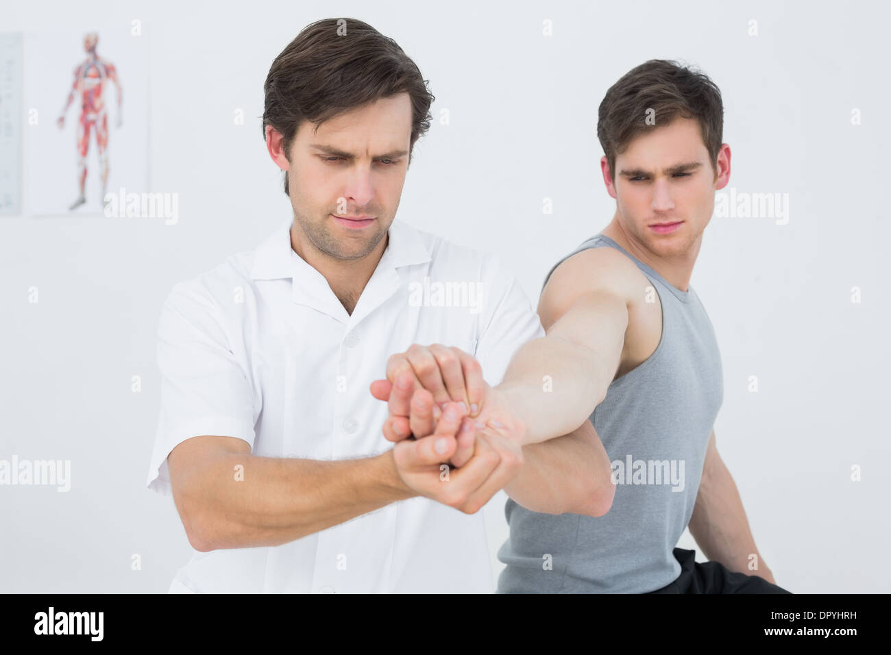 Fisioterapista maschio esaminando un giovane mans mano Foto Stock