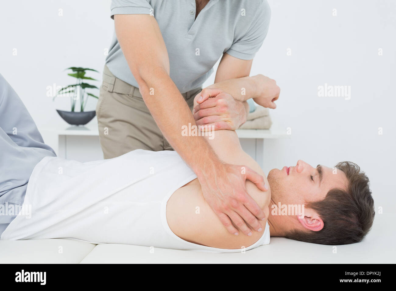Fisioterapista maschio esaminando un mans mano Foto Stock