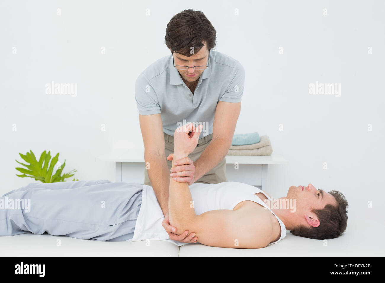 Fisioterapista maschio esaminando un giovane mans mano Foto Stock