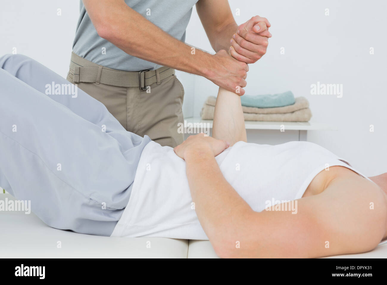 Fisioterapista maschio esaminando un giovane mans polso Foto Stock