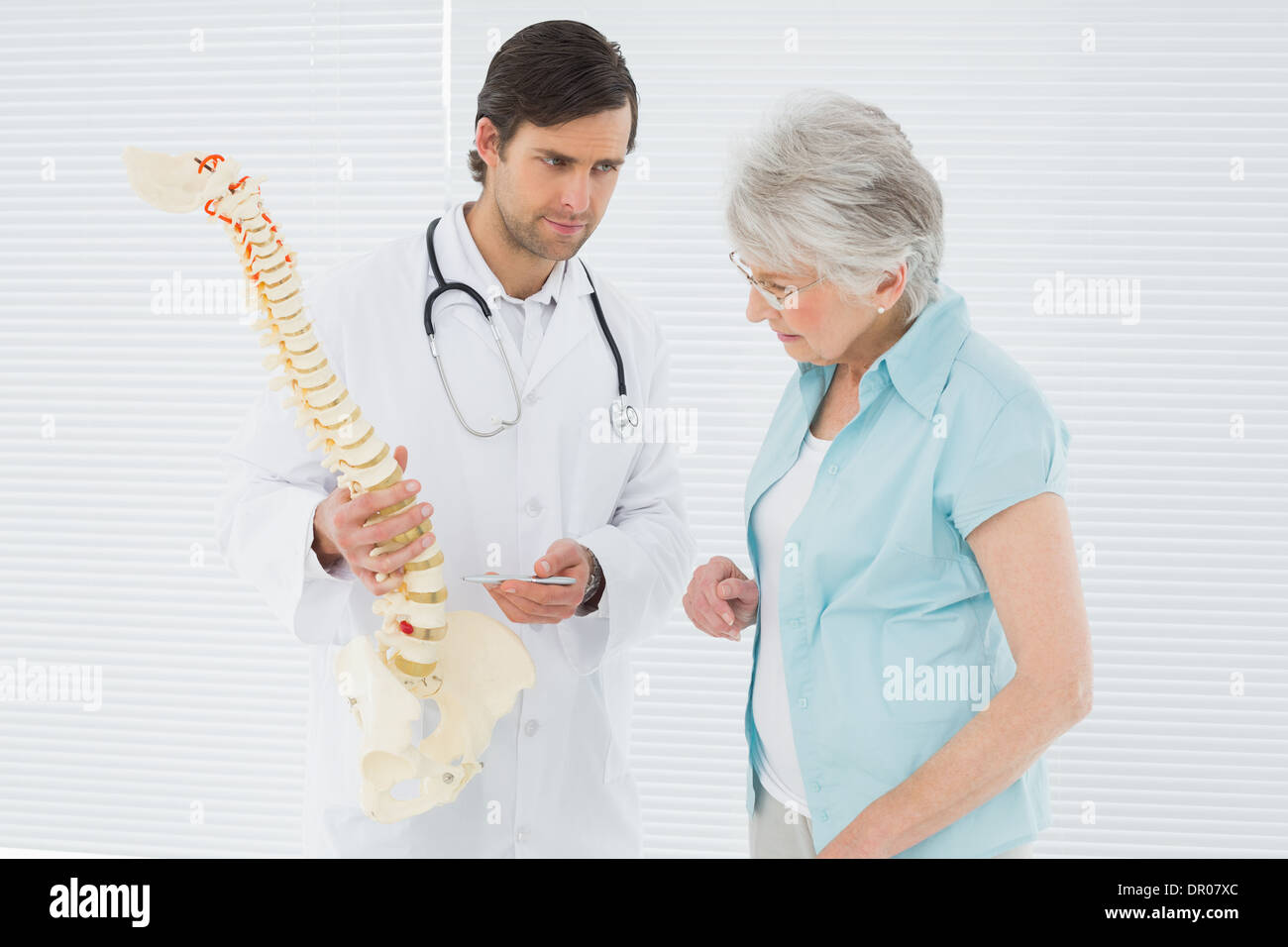 Medico spiegando la colonna vertebrale di un paziente senior Foto Stock