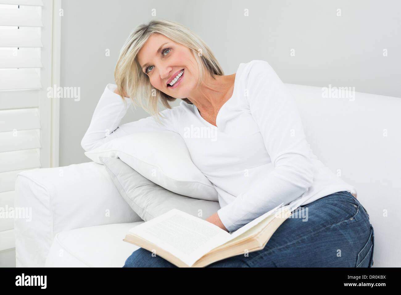 Donna felice con un libro a casa Foto Stock