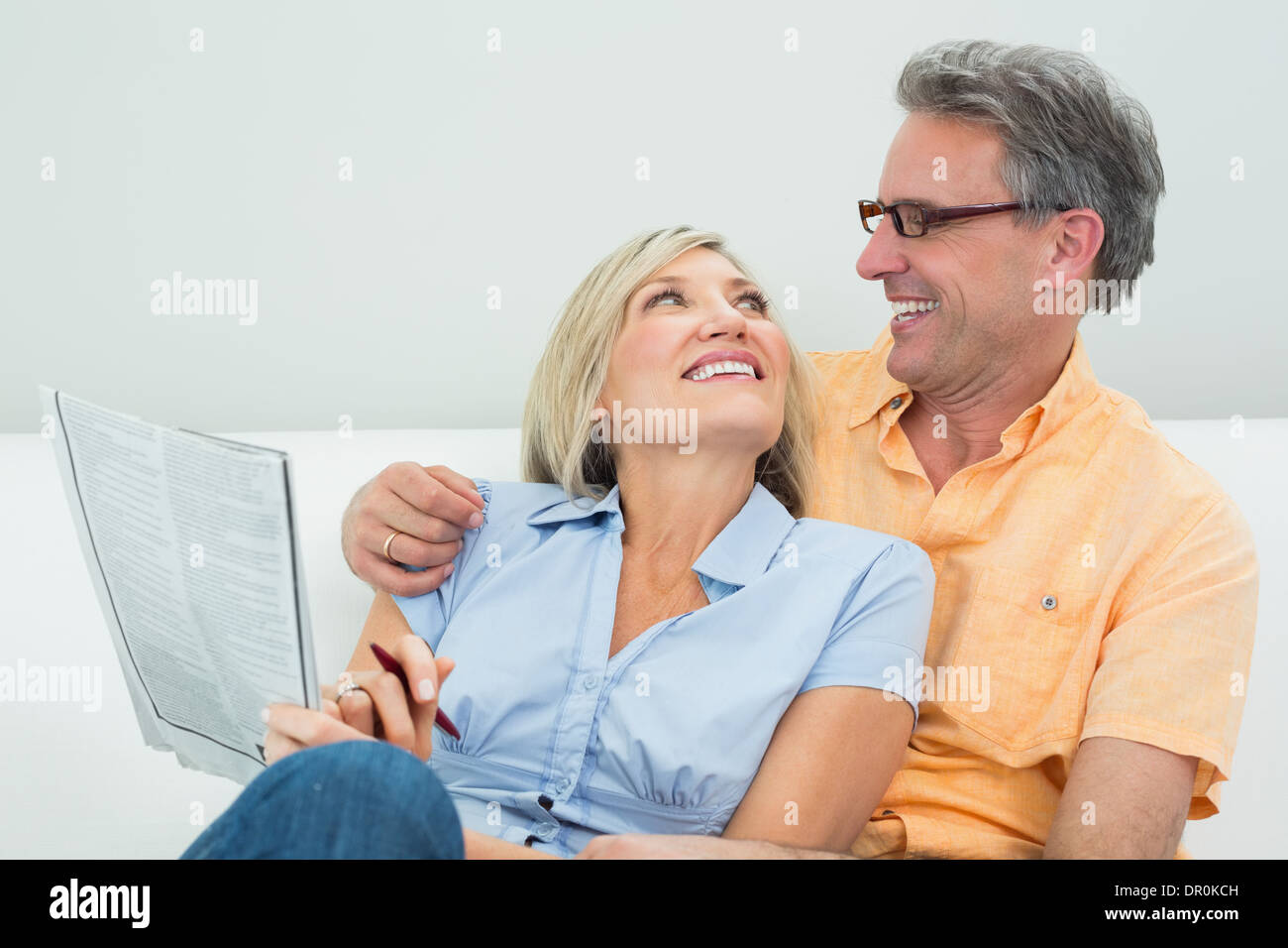 Coppia felice con il giornale in soggiorno Foto Stock